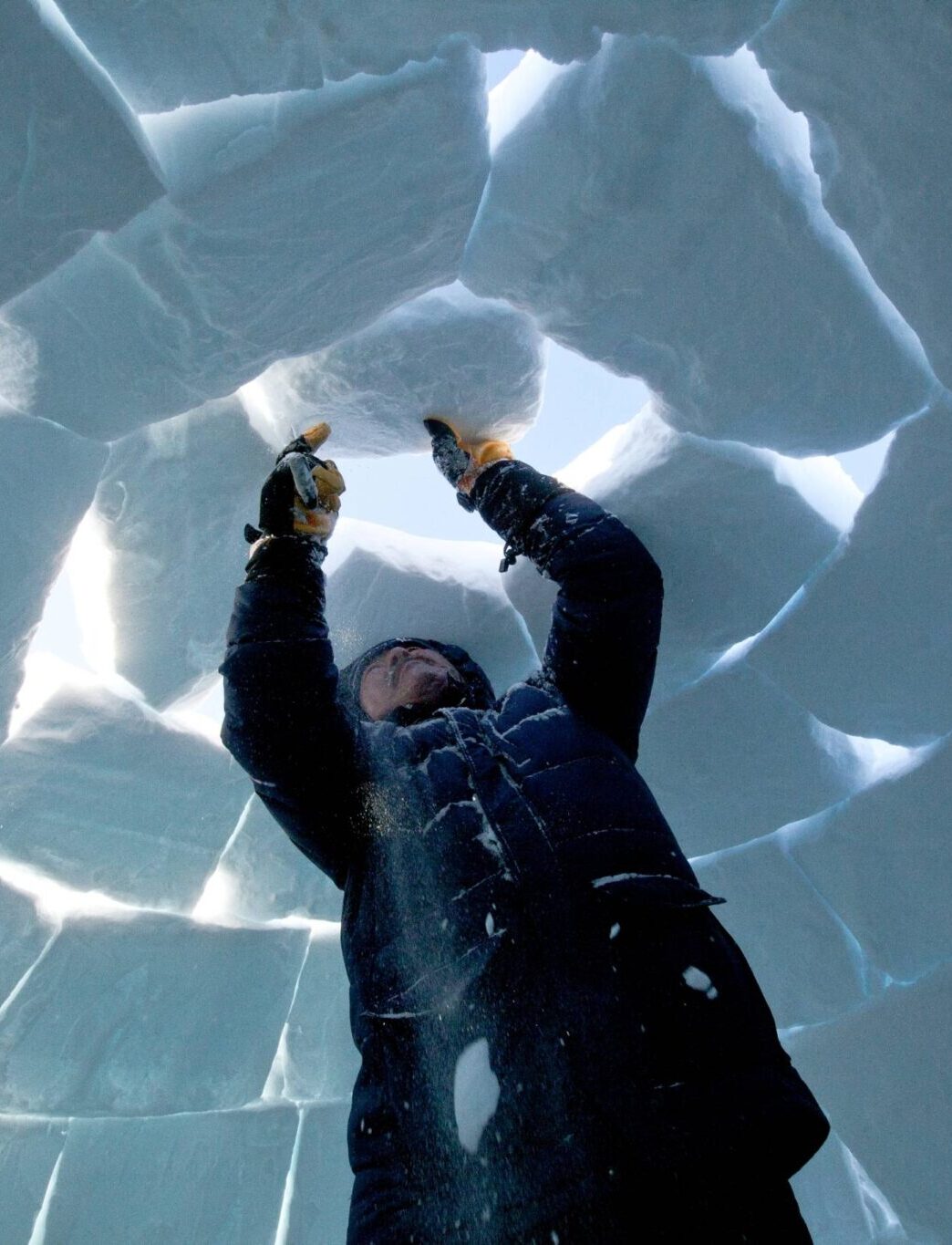 man assembling an igloo from above